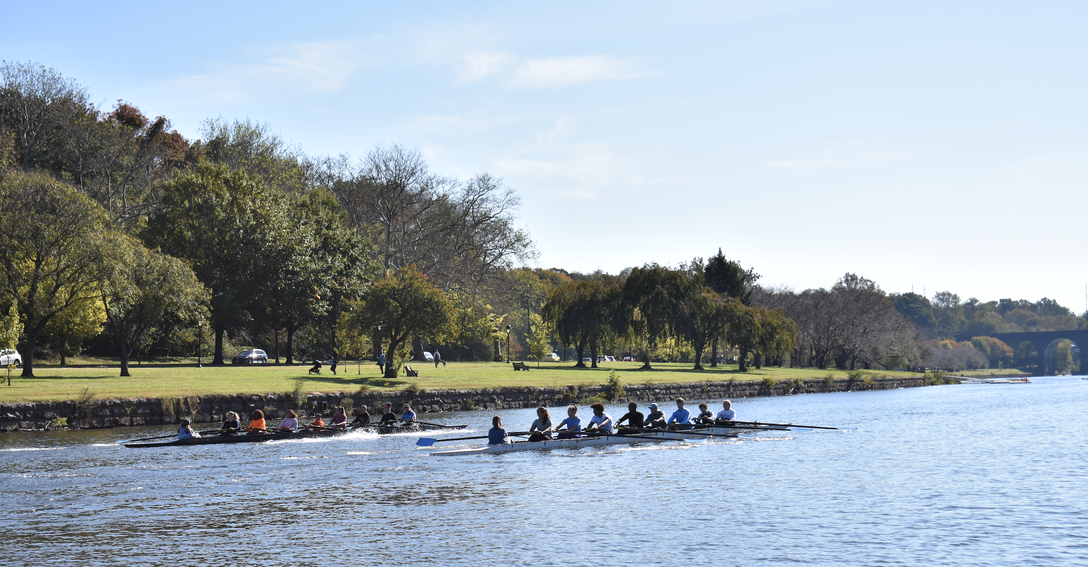 Two PCR boat rowing on beautiful fall day with sun glistening off water